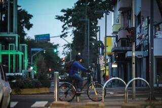 Bem agasalhado, ciclista atravessa trecho da Rua 14 de Julho (Foto: Henrique Kawaminami)
