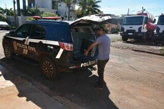 Policial coloca na viatura computador apreendido na casa de professor, em Maracaju (Foto: Divulgação)