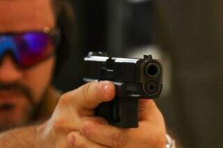 Homem manuseia arma em clube de tiro de Campo Grande. (Foto: Henrique Kawaminami)