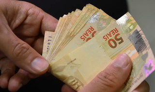 Pensionista contabiliza diversas cédulas de R$ 50. (Foto: Marcello Casal Jr./Agência Brasil)