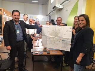 Prefeita e executivos da Caixa segurando mapa de Campo Grande durante a reunião (Foto: Fernanda Palheta)