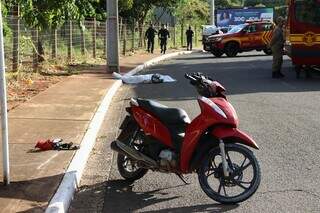 Motocicleta da vítima e equipes do Corpo de Bombeiros no local do acidente (Foto: Osmar Veiga)