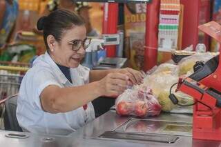 Sorridente, caixa de supermercado passa as compras do cliente (Foto: Marcos Maluf) 