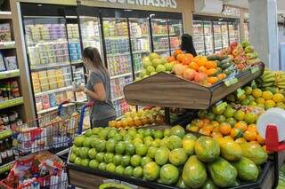 Consumidora, com carrinho cheio, olhando produtos lácteos em freezer de supermercado (Foto: Marcos Maluf)