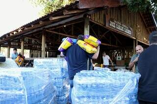 Voluntários carregam sacos de ração e fardos de água que serão levados para RS (Foto: Osmar Daniel)