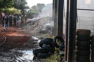 Bombeiros contendo incêndio nas toras de madeira que ficam na área externa do depósito (Foto: Marcos Maluf) 
