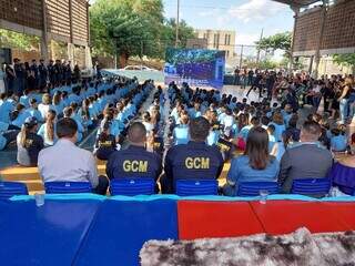 Comando da Guarda e prefeita de costas, com alunos da Escola Municipal Governador Harry Amorim Costa.
