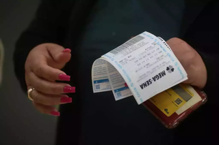Apostadora segura comprovantes de aposta da Mega-Sena em lotérica de Campo Grande (Foto: Marcos Maluf)
