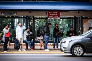 Em ponto de ônibus da Rua 14 de Julho: de sete passageiros, três arriscam deixar as pernas &#34;de fora&#34; na manhã de 17ºC (Foto: