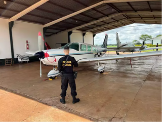 Agente da PF ao lado do avião de Mendes; aeronave foi apreendida em dezembro (Foto: Arquivo)