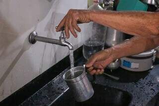 Dona de casa usando água da torneira para encher copo de alumínio (Foto: Paulo Francis)