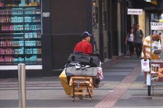 Ambulante atravessando a rua carregando pertences para vender (Foto: Alex Machado)