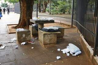 Em uma das mesas na praça, saco foi aberto e lixo espalhado, nesta tarde (Foto: Paulo Francis)