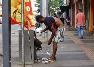 Homem é flagrado remexendo lixo em frente à praça: problema social que se soma ao cenário do Centro (Foto: Paulo Francis)