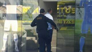 Agente do Gaeco entra em loja de uniformes esportivos, na Rua José de Alencar (Foto: Leandro Holsbach)