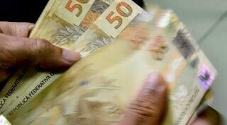 Homem conta notas de 50 reais. (Foto: Marcello Casal Júnior/Agência Brasil)