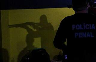 Sombra de policial penal enquanto manuseia uma espingarda. (Foto: Juliano Almeida)