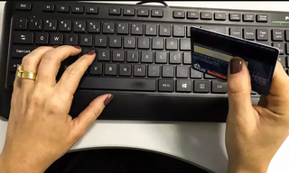 Consumidora com cartão de crédito na mão para fazer compras online (Foto: Agência Brasil)