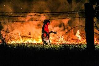 Bombeiro combate incêndio na noite de sexta-feira, em Campo Grande. (Foto: Juliano Almeida)