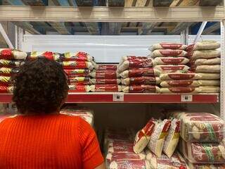 Terezinha olhando prateleira com pacotes de arroz (Foto: Clara Farias)