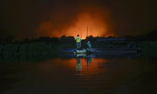 Incêndios sendo observados por brigadistas em barco no Pantanal (Foto: Joédson Alves/Agência Brasil) 