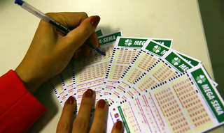 Apostadora preenche volante de apostas da Mega-Sena em uma agência lotérica da Caixa. (Foto: Marcello Casal Jr./Agência Brasil)