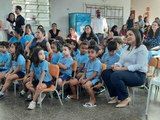 Prefeita Adriane Lopes sentada ao lado de crianças, na Emei Paulo Siufi (Foto: Caroline Maldonado)