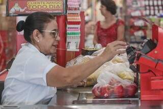 Operadora de caixa de atacadista passando compras de clientes (Foto: Marcos Maluf)
