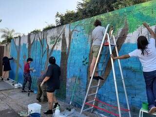 Artistas e acadêmicas de Geografia da UEMS trabalhando na pintura (Foto: Divulgação)