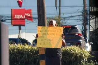 Imigrante venezuelano segura cartaz pedindo ajuda na rotatória da Mato Grosso. (Foto: Arquivo/ Henrique Kawaminami)