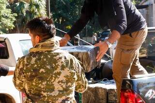 Agentes da Senad carregam fardos de droga apreendidos na fronteira (Foto: Divulgação)