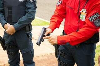 Policial Militar mostrando pistolas de 9 mm, compradas pelo Governo do Estado no ano passado (Foto: