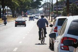 Ciclista pedala próximo a carros estacionados na Avenida Gunter Hans. (Foto: Henrique Kawaminami)