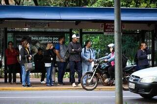 Pessoas com casaco esperando ônibus em ponto na Praça Ary Coelho (Foto: Henrique Kawaminami) 