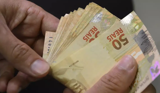Homem conta notas de R$ 50 verdadeiras (Foto: Agência Brasil)