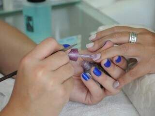 Manicure pintando unha da mão de cliente (Foto: Paulo Francis)