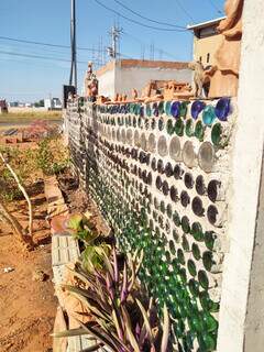 Muro decorado com garrafas e vários itens de cerâmica em cima do muro (Foto: Arquivo Pessoal)