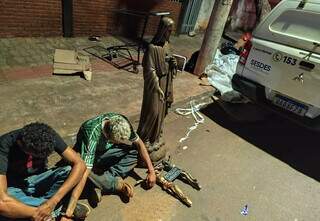 Ladrões algemados, sentados na rua ao lado das estátuas furtadas (Foto: Divulgação)