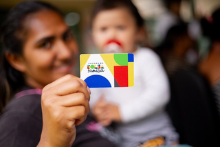 Mãe segura cartão do bolsa família (Foto: Divulgação)