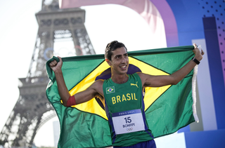Caio segura a bandeira brasileiro após a prova (Foto: Alexandre Loureiro/COB)