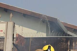 Do muro vizinho, moradora joga água para ajudar a apagar o fogo (Foto: Osmar Veiga)