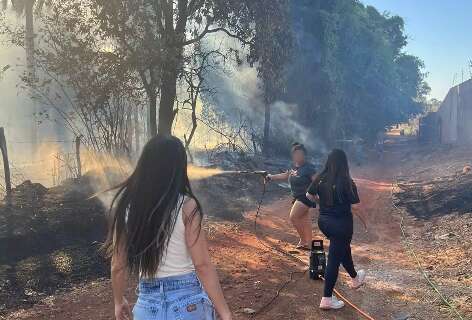 Moradores de condomínio puxam mangueiras para apagar fogo em terreno