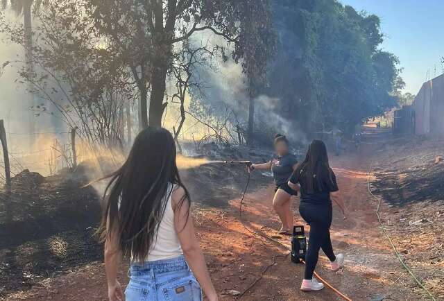 Moradores de condom&iacute;nio puxam mangueiras para apagar fogo em terreno