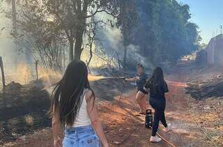 Moradores tentando apagar fogo com mangueira (Foto: Reprodução)