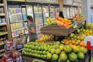 Consumidora, com carrinho cheio, olhando produtos lácteos em freezer de supermercado (Foto: Marcos Maluf/Arquivo)