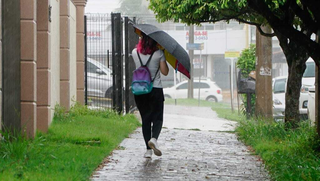 Jovem usa guarda-chuva para transitar nas ruas da Capital. (Foto: Alex Machado/Arquivo do Campo Grande News)