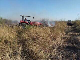 Tratores fazem a abertura dos aceiros no Pantanal de MS, ao lado de pequeno foco de incêndio (Foto: Divulgação/Governo de MS)