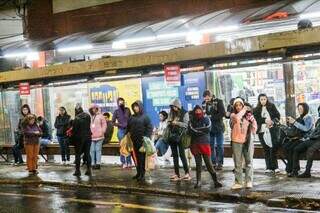 Pessoas aguardando ônibus em ponto na região central nesta sexta-feira (Foto: Juliano Almeida)