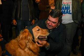 Riedel acaricia cão da raça Golden Retriever durante solenidade. (Foto: Bruno Rezende/Agência MS de Notícias)