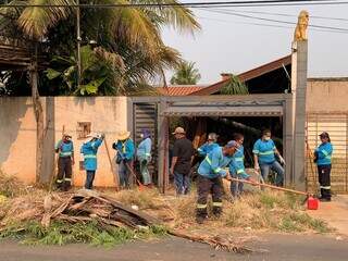 Trabalhadores da Sisep fazendo a limpeza na área externa da residência (Foto: Bruna Marques) 